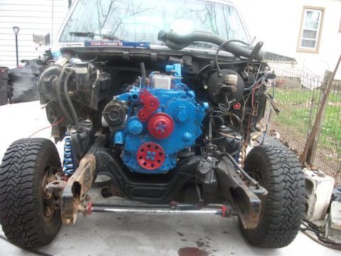 1990 Ford Bronco - The front end of a vehicle is shown with its body panels removed, revealing a newly installed blue engine.