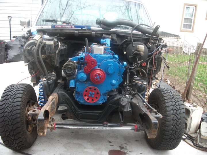 Disassembled vehicle front end with a bright blue engine installed