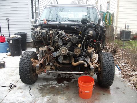 1990 Ford Bronco - The front end of a 1990 Ford Bronco is shown with its engine removed, revealing the chassis and suspension components.