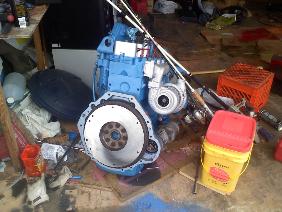 blue engine with turbo and flywheel, fishing rods, buckets, and other garage items