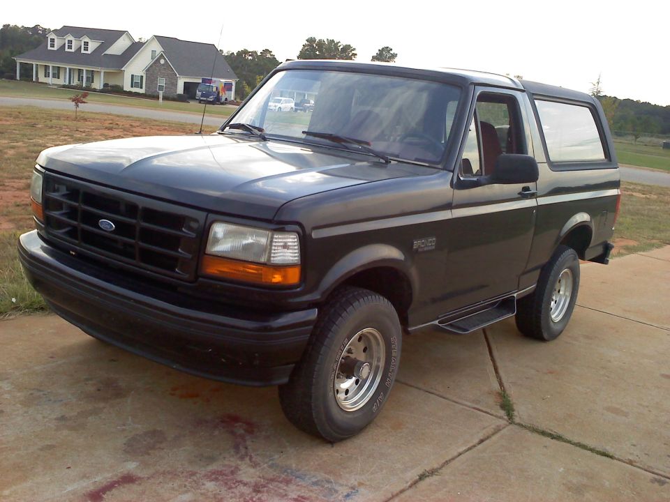 Black Ford Bronco parked on a concrete driveway, front 3/4 view