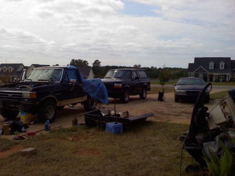 1995 Ford Bronco - Several vehicles are parked in a driveway with houses in the background.