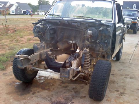1995 Ford Bronco - This truck's front end is disassembled, revealing the chassis and suspension components. Another truck is visible in the background.