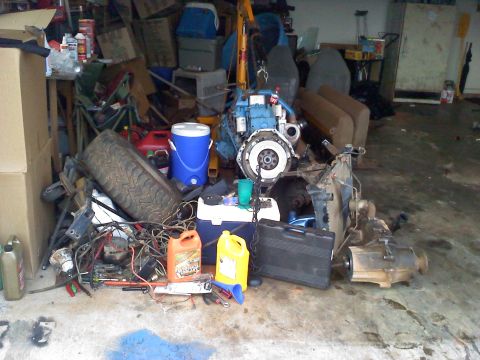 1995 Ford Bronco - Various automotive parts including an engine and transmission are stored in a cluttered garage.