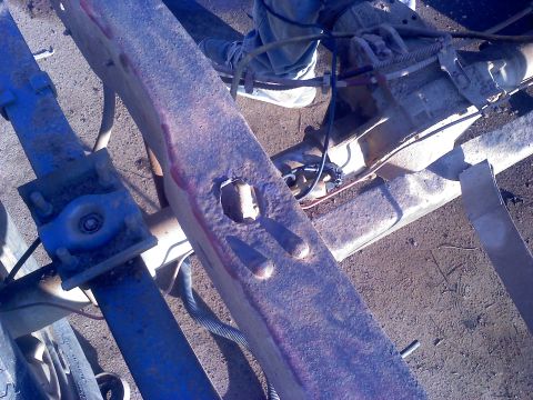1995 Ford Bronco - Close-up of a vehicle's frame and suspension components, showing rust and some blue painted parts.