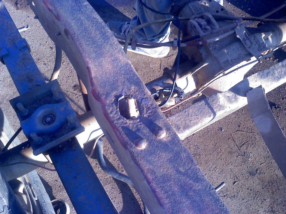 Rusty metal frame with blue suspension parts and wiring. Close-up view