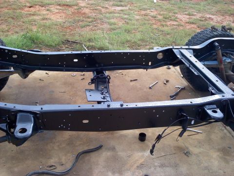 1995 Ford Bronco - The frame of a vehicle is shown, with a tire visible on the right side. Tools are scattered around.