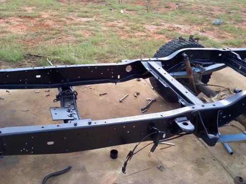 1995 Ford Bronco - The frame of a vehicle is shown from a side angle, with tools scattered around.