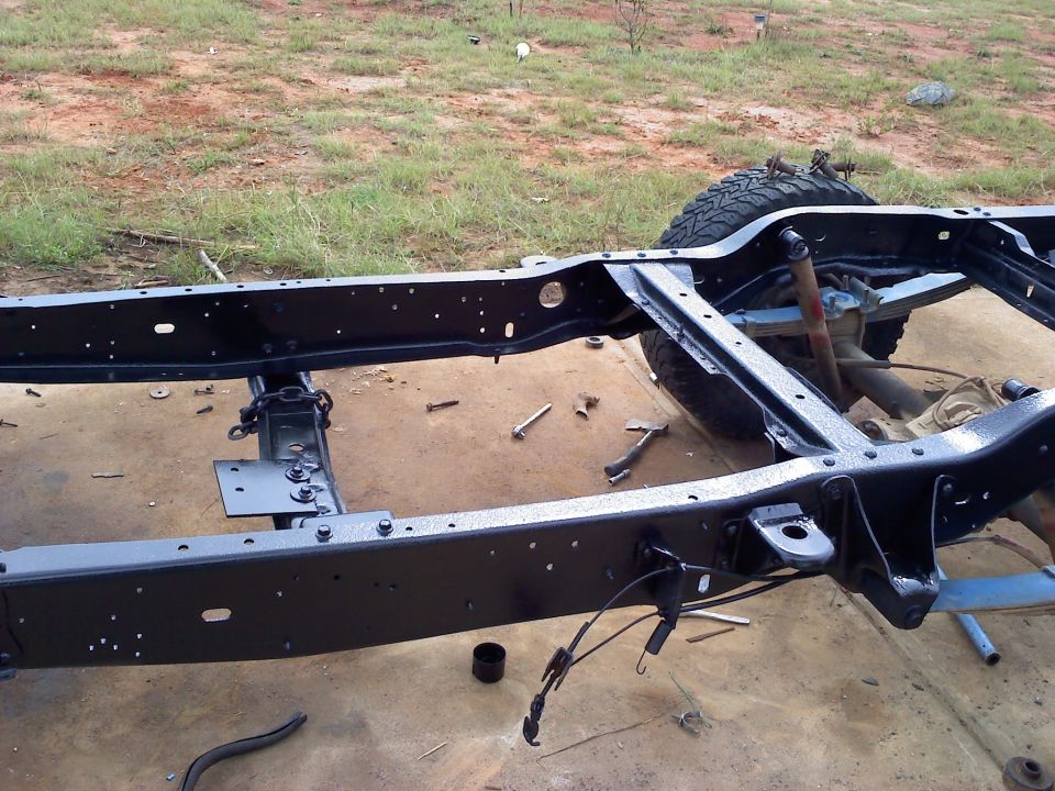 Black painted vehicle frame with suspension components and a tire visible