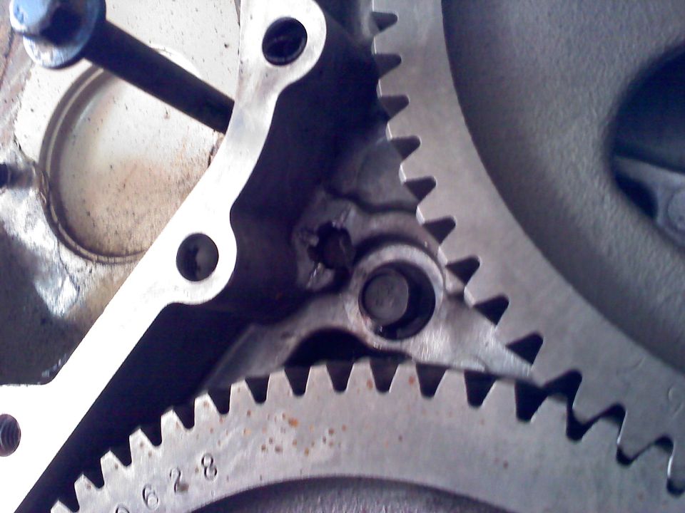 Close-up of two meshing metal gears, one with visible part numbers
