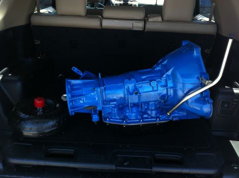 1982 Ford Bronco - A bright blue transmission and torque converter are stored in the back of a vehicle.