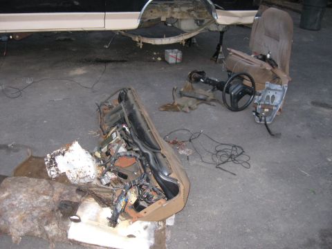 1990 Ford Bronco - Interior components, including the dashboard and a seat, are disassembled and laid out on the ground.