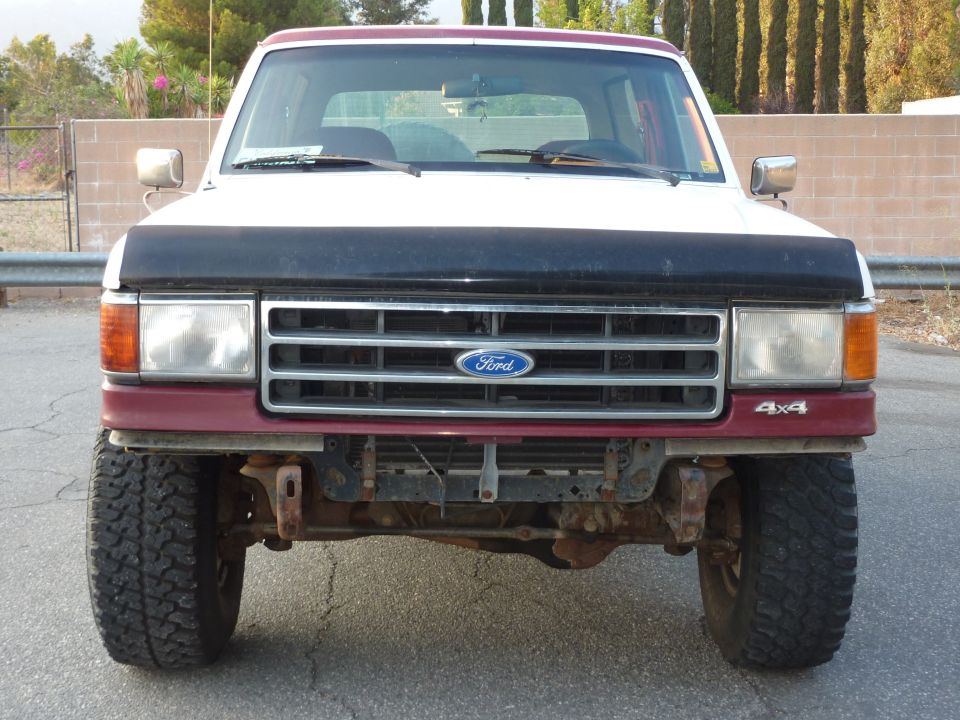 White and burgundy Ford 4x4 front view, hood bra on, front bumper removed