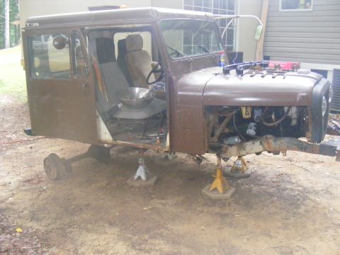 1978 Ford Bronco - This is a brown, vintage vehicle, possibly a truck or SUV, undergoing restoration. The vehicle is on jack stands with its front end disasse…