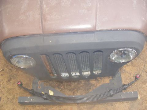 1978 Ford Bronco - A close-up view of the front end of a vehicle, likely a Jeep or similar off-road vehicle, showing the grille, headlights, and a leaf spring…