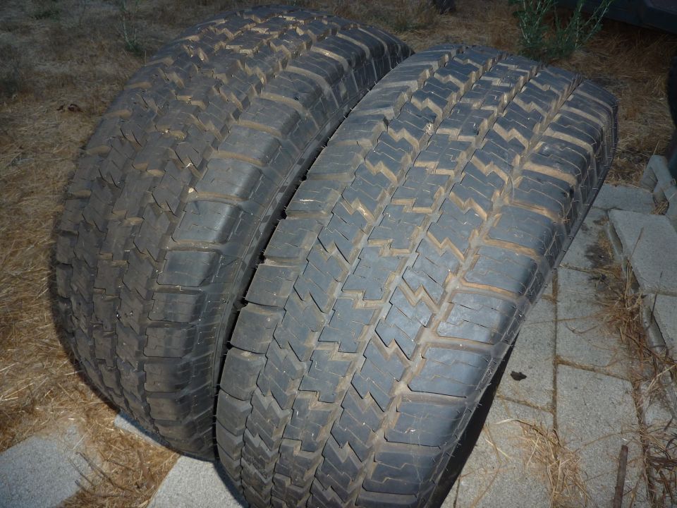 Two used tires, one with an aggressive tread pattern, lying on the ground.