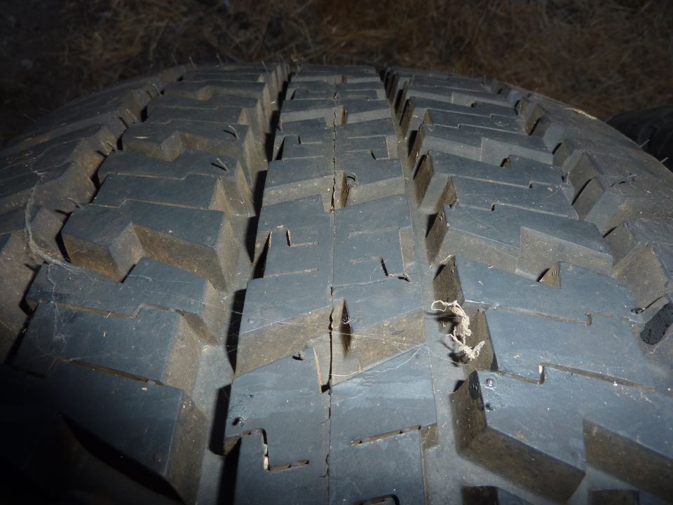 Close-up of a worn tire tread with debris stuck in it.