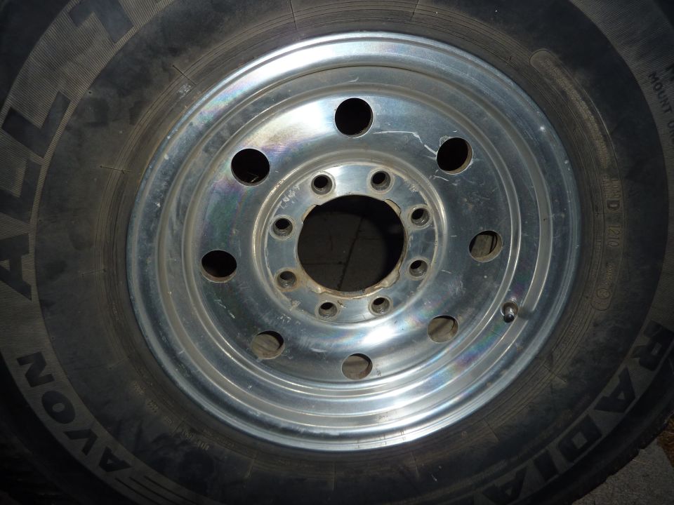 Close-up of a tire and silver alloy wheel with lug nut holes.