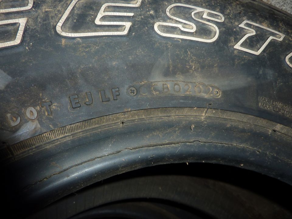 Close-up of a tire sidewall with DOT markings and manufacturing code.