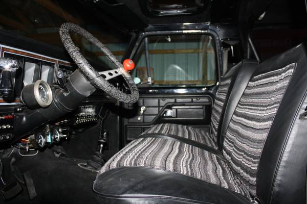 Interior of a vintage Ford Bronco showing steering wheel, dashboard, and striped seat.