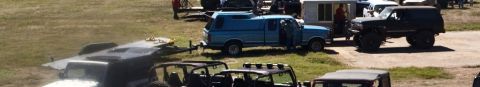 1995 Ford Bronco - A lifted black Ford Bronco is parked on a dirt road next to a white trailer and a blue pickup truck with a camper shell. The Bronco has lar…