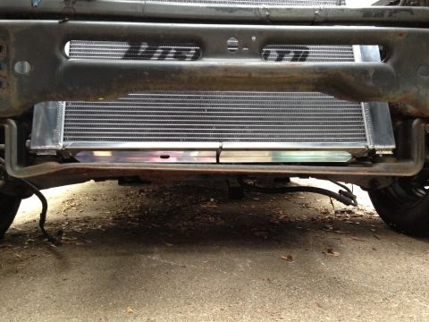 2004 Ford Crown Victoria - A low-angle view of the front underside of a vehicle, showing a large, new aluminum radiator installed behind the bumper structure. The rad…