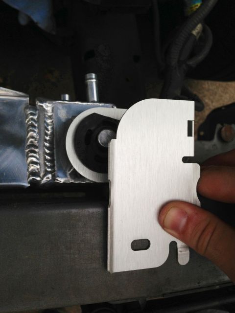2004 Ford Crown Victoria - A person's hand holds a brushed metal bracket near a silver radiator with visible welds. The bracket has a cutout shape and an oval slot, a…
