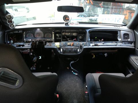 2004 Ford Crown Victoria - The interior of a disassembled 2004 Ford Crown Victoria dashboard is shown, with the instrument cluster and center console partially remove…