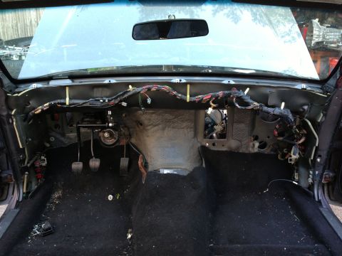 2004 Ford Crown Victoria - The interior of a disassembled car, likely a sedan, shows the dashboard removed, exposing the wiring harness and pedals. The floor is cover…
