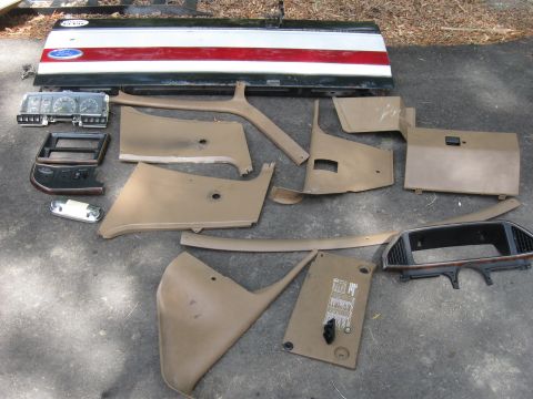 1990 Ford Bronco - Various interior trim pieces and a tailgate are laid out on the ground, likely for a 1990 Ford Bronco. The tailgate features a red and whit…