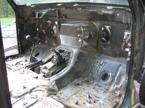 1990 Ford Bronco - The interior of a disassembled 1990 Ford Bronco shows the rusted floor pan, transmission tunnel, and firewall. The shifter levers and part…