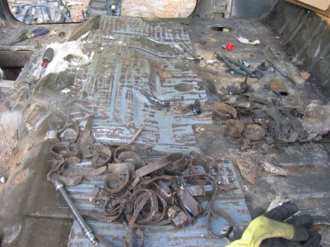1990 Ford Bronco - The interior floor of a vehicle is shown, appearing to be undergoing a restoration or clean-out. Various metal debris, insulation, and tool…