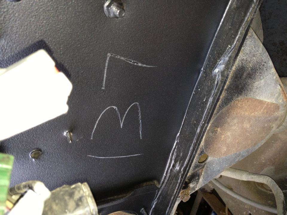 chalk markings 'L' and 'M' on black painted metal part of a vehicle