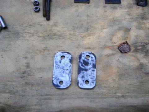 1978 Ford Bronco - Two metal plates and hardware are laid out on a wooden surface.