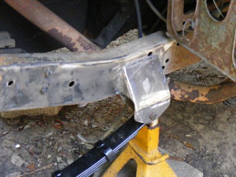 1978 Ford Bronco - A close-up view of a vehicle's frame and suspension components, supported by a yellow jack stand.