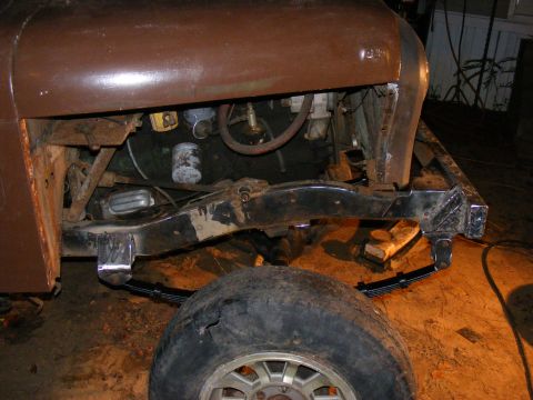 1978 Ford Bronco - This image shows the engine bay and frame of a vehicle undergoing work, with a front wheel and suspension visible.
