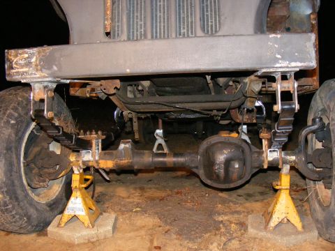 1978 Ford Bronco - The front axle and suspension components of a vehicle are shown, elevated on jack stands for maintenance.