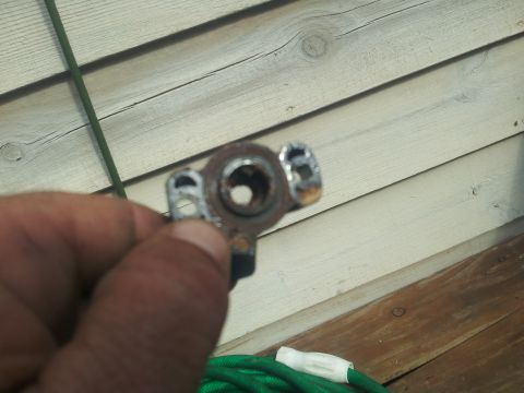 1988 Ford Bronco - A metal part is held in a hand against a wooden wall background.