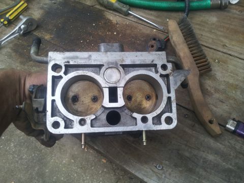 1988 Ford Bronco - Carburetor part being held, with tools visible in the background.