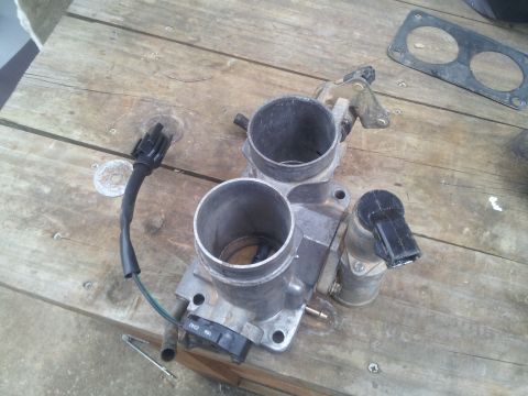 1988 Ford Bronco - A throttle body part is shown on a wooden table, with visible text at the bottom right.