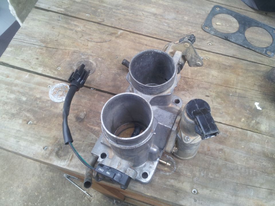 Throttle body with dual bores and electrical connectors on a wooden surface