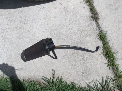 1995 Ford Bronco - An oil filter with a bent metal hose attached is shown on a concrete surface with grass growing in the cracks.