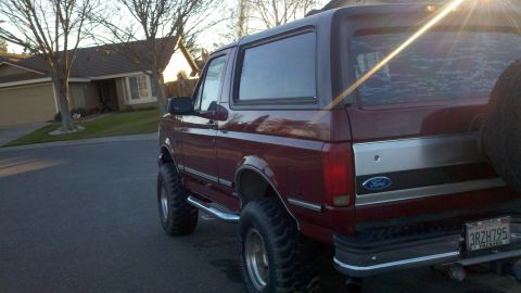 1992 Ford Bronco - Maroon 1992 Ford Bronco with aftermarket wheels and tires, parked in front of a house.