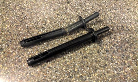 1994 Ford Bronco - Two black plastic push-pin retainer clips lying on a speckled countertop, each with a slotted split shank, flanged collar and tapered pin,…