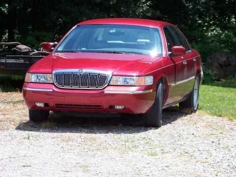 1999 Mercury Grand Marquis - Front view of a red sedan with a prominent chrome grille.