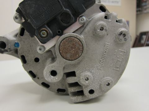 2001 Ford Crown Victoria - Close-up of a Motorcraft alternator, showing the 'GROUND HERE TO TEST' label and various mounting points.