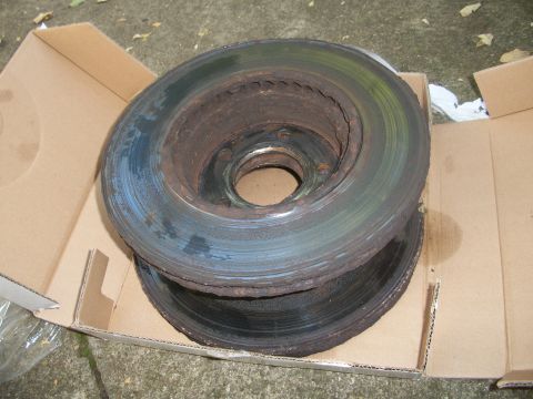 2001 Ford Crown Victoria - Two heavily rusted brake rotors are shown in a cardboard box, indicating wear and tear.