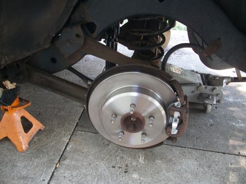 2001 Ford Crown Victoria - Close-up view of a vehicle's rear suspension and brake system, with a jack stand and floor jack visible.