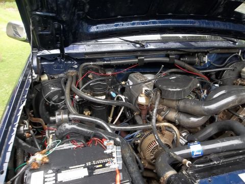 1995 Ford Bronco - Close-up view of the engine compartment of a blue vehicle, showing various engine components.
