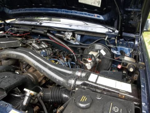 1995 Ford Bronco - Close-up view of the engine compartment, revealing various mechanical parts and wiring harnesses.